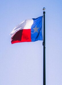 The Texas state flag waving against a clear blue sky in Houston, representing the local market for how to sell a small business in Houston.