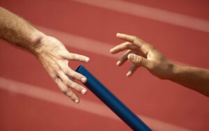 A relay race handoff representing a messy or fumbled handoff during a critical transition, highlighting the risks of poor family business exit planning.