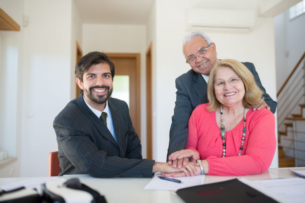 Two generations of family business owners celebrating a successful deal at a table, highlighting smooth family business exit planning and succession.